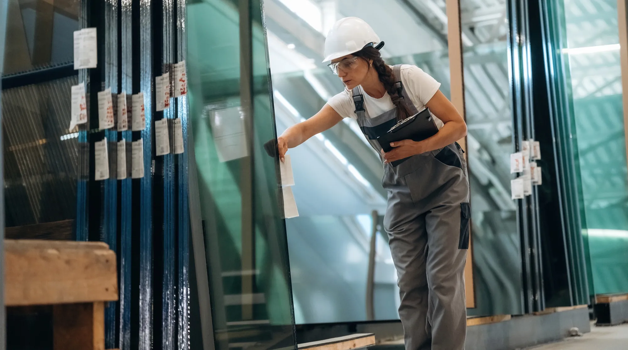 A glazier fitting a large pane of glass into a window frame
